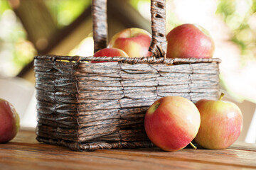 Ripe apples in a basket and on a wooden table
