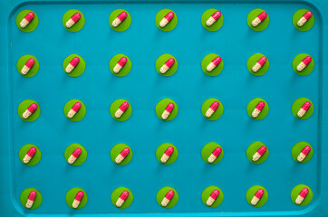 The white and red capsules lie in straight rows on green circles and a blue background.Pills,pills, medicines.medicine and healthcare.treatment.Texture and pattern.Background and template.presentation