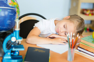 Small girl sleeping on a desk in a classroom