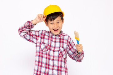 Little kid as a construction worker wearing yellow helmet with a paintbrush in his hand..White background studio picture.