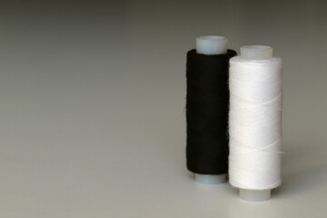 Fototapeta na wymiar A spool of white and black sewing threads
