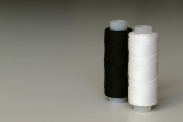 A spool of white and black sewing threads