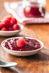Red rasberries jam in bowl and ripe raspberries.