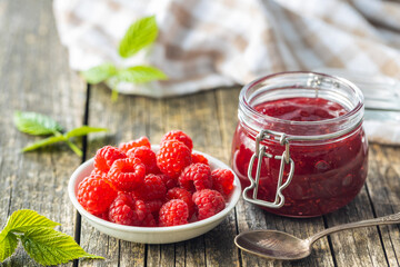 Red rasberries jam in jar and ripe raspberries.