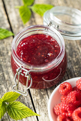 Red rasberries jam in jar and ripe raspberries.