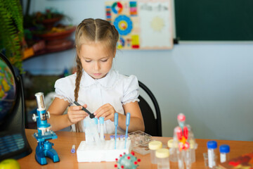 Young girl making science chemistry experiments in school laboratory. Education concept