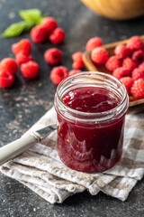 Red rasberries jam in jar and ripe raspberries.