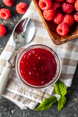 Red rasberries jam in jar and ripe raspberries.