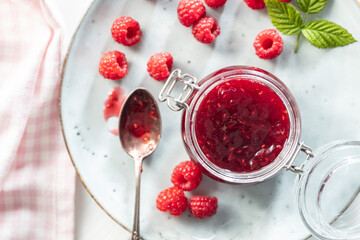 Red rasberries jam in jar and ripe raspberries.