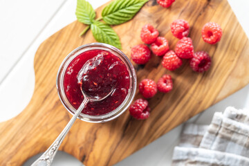 Red rasberries jam in jar and ripe raspberries.
