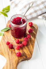 Red rasberries jam in jar and ripe raspberries.
