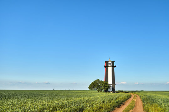 Black and white lighthouse in a wheat green field