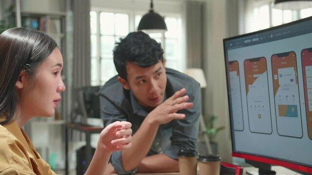 Asian Female Ux Architect Has Discussion With Male Design Engineer, They Work On Mobile Application In Office
