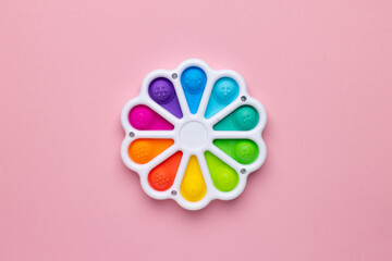 Presses with a finger anti-stress toy pop it on pink background. Colorful silicone poppit toy, bubble fidget, simple-dimple