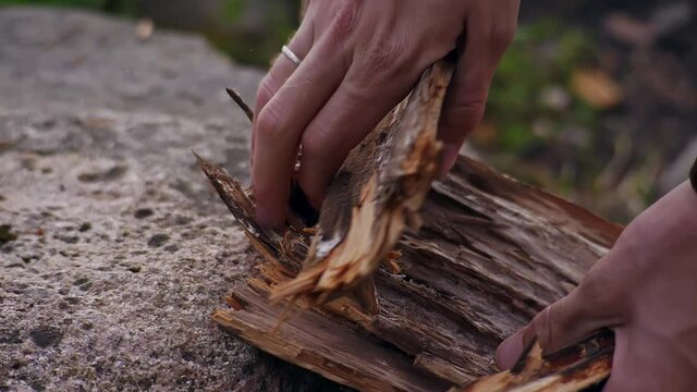 Young traveler puts wood on to light the fire in nature in the forest. Hands with a wedding ring close up. Camping. Hiking in the mountains. Tourism. Travel