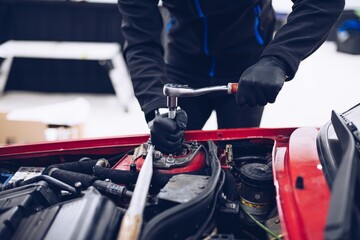 Car mechanic in service repairing engine with wrench