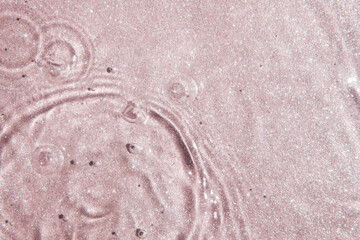 Pink water background, texture with drops and waves with glittering