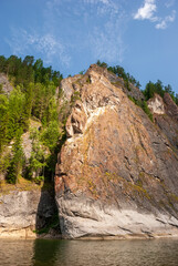 Landscape of Siberia. Kiya River, mountain banks and green forests in the Kemerovo region. Daytime landscape with blue skies and clouds.