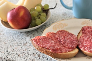 closeup sandwich with smoked sausage cup of tea and fruits dinner meat