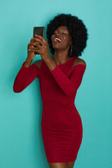 Happy Black Woman In Elegant Dress Is Holding Telephone And Looking At It