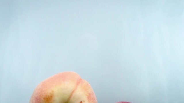 Closeup 4k footage of donut peaches falling in water against white backgorund.