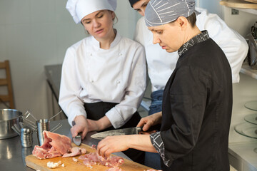 Cooking classes. The chef teaches trainees to cut chicken - 447781442