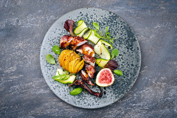 Modern style Italian polpo alla griglia su patatine fritte with barbecued octopus, potato chips and fresh fruits as top view on a Nordic design plate with copy space