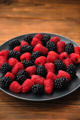 Fresh organic summer berries mix in round black table