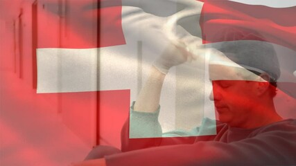 Digital composition of switzerland flag waving over stressed caucasian male surgeon at hospital - Powered by Adobe