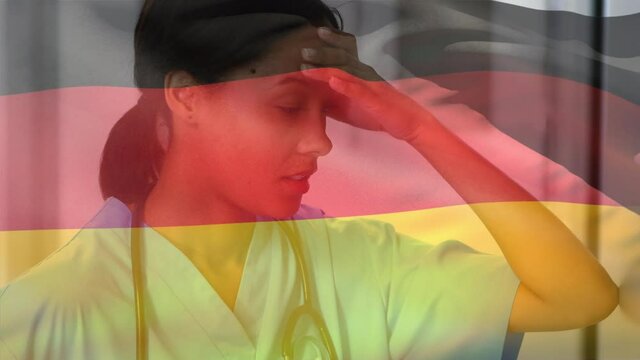 Germany flag waving against stressed african american female health worker at hospital
