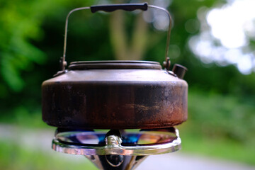 black tourist kettle boils water on a gas burner, camping food cooking concept, romantic breakfast...