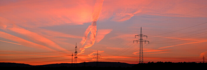 beautiful landscape, sky with airplane trail lines, power towers, field in evening in rays of sunset, concept of beauty of nature, modern energy, technology, bright wallpaper, background for designer