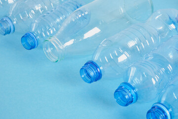 one glass bottle among several plastic bottles on a blue background