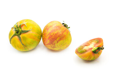 Two fresh ripe organic striped zebra tomatoes whole and half isolated on white background.	