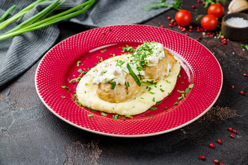 Chicken cutlets with mashed potatoes on red plate on dark concrete table