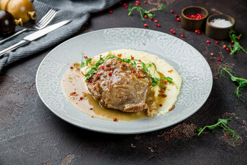 Beef cheeks with mashed potatoes on grey plate on dark concrete table