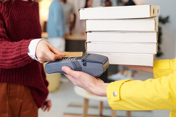 Young smiling blond female holding credit card over screen of payment machine