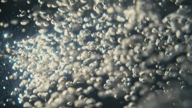 Video of underwater colorful bubbles rising to surface in slow motion 180fps. Close up, refreshing soda tonic fizzy water, bubbles dissolve in mineral carbonated drink. Bubbles particles rise up.
