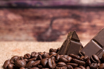 Stack of chocolate chunks with coffee beans on a wooden background, horizontal with copy space