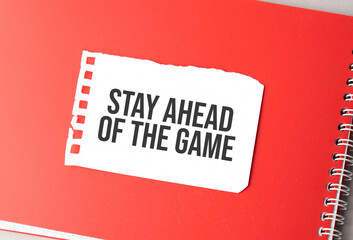 The word Stay Ahead of The Game on torn paper on red notepad,.