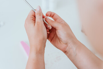 Maniküre der Fingernägel mit Feile. Junge Frau macht schöne Nagelpflege vor Füllung mit Acryl 