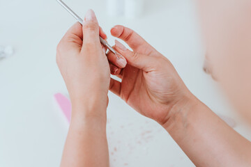 Maniküre der Fingernägel mit Feile. Junge Frau macht schöne Nagelpflege vor Füllung mit Acryl 