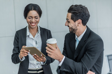 secretary presents  tablet showing schedule of appointments to  manager or boss by hold cup coffee