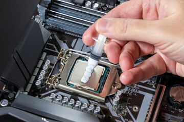 A technician applies white thermal paste to the CPU. Installing a cooler on a PC processor....