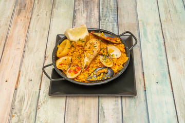 One-person paella with seafood paella with a delicious aspect, with its crayfish, mussels and clams and squid rings with fried peppers and lemon and saffron dressing