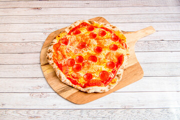 Super spicy Italian pepperoni pizza with wheat flour thin crust and mozzarella cheese on white wooden table