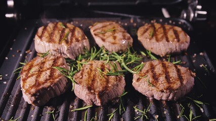 Delicious juicy meat steak cooking on grill. Aged prime rare roast grilling tenderloin fresh marble tenderness beef. Prime beef fry on electric roaster, rosemary, black pepper, salt. Slow motion.