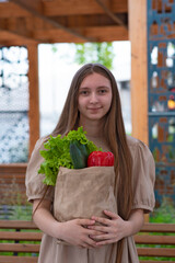 beautiful  teen girl with long hair holds paper bag with vegetables
