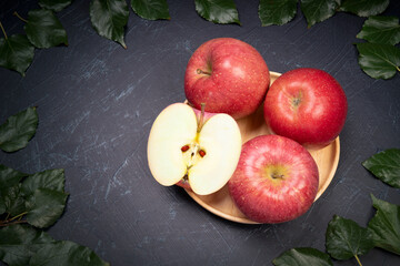 San Fuji Apples in wooden basket on wooden table in garden, Pink Apple with leaves in wooden background.