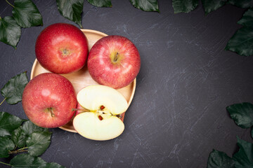 San Fuji Apples in wooden basket on wooden table in garden, Pink Apple with leaves in wooden background.